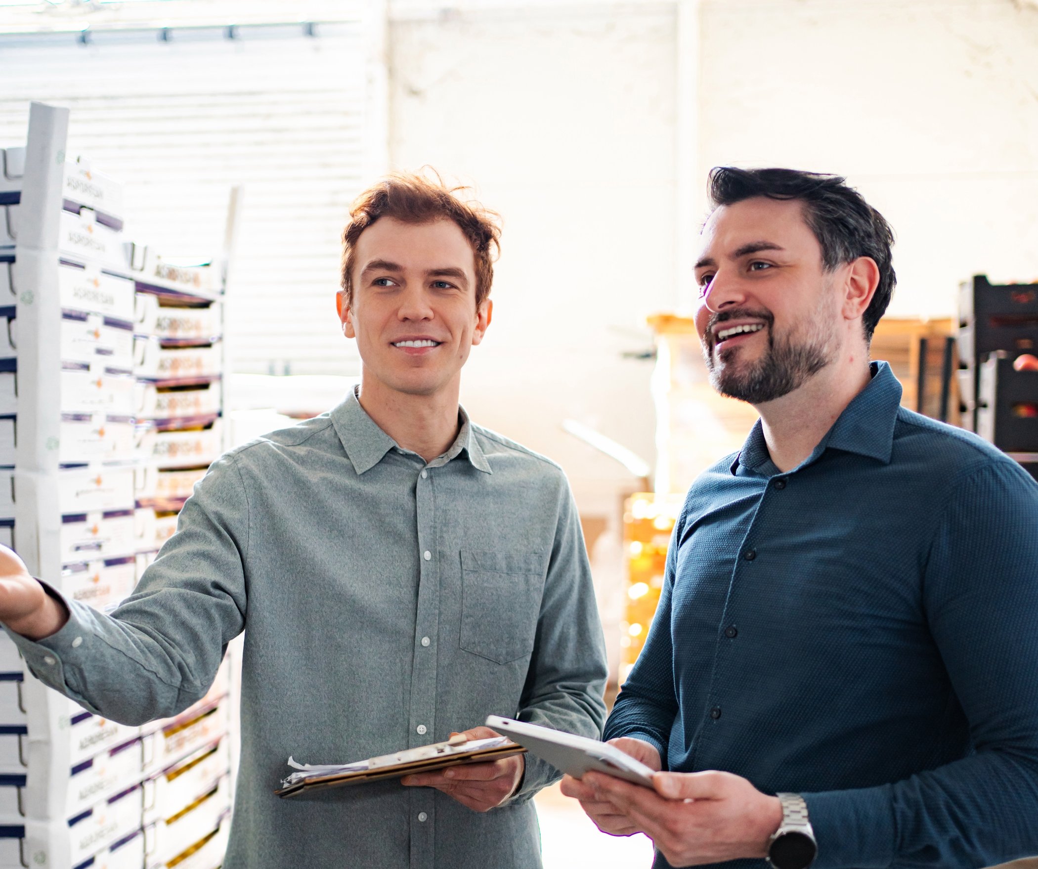 Two colleagues reviewing inventory with a tablet in a distribution warehouse